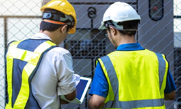 Dois trabalhadores de campo inspecionam as concessionárias da rede elétrica