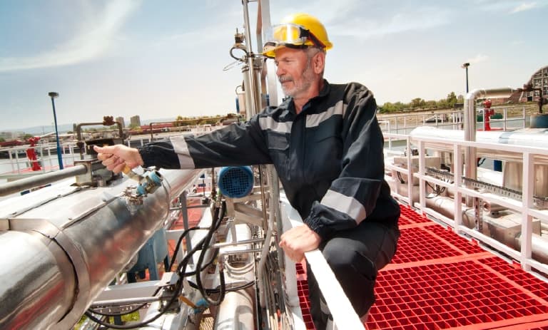 Trabalhador de campo próximo a grandes tubulações