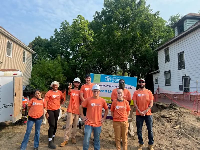Equipe de voluntários da Qualitrol em camisetas laranja no canteiro de obras da Habitat for Humanity