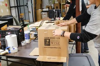 Voluntários da Qualitrol empacotando caixas de doações na mesa